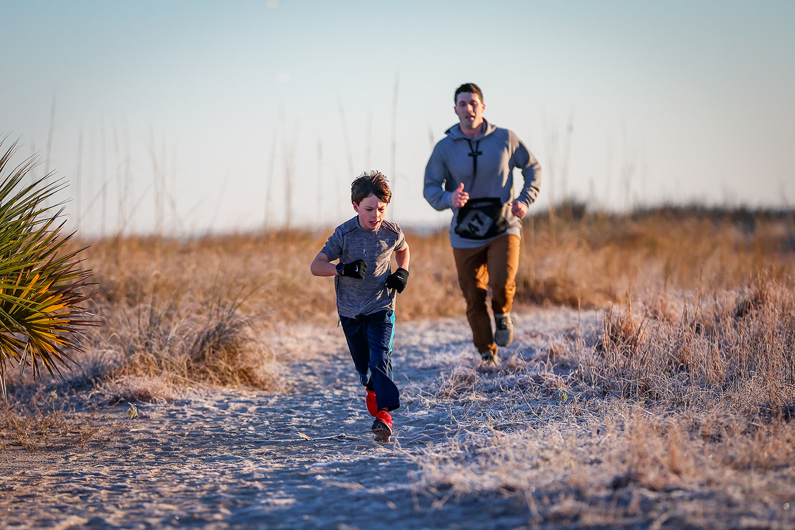 Father and child running together on sandy trail