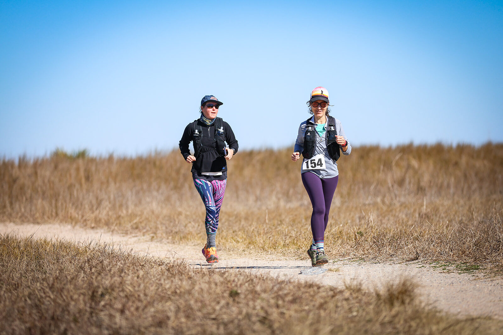 Two women running together on coastal path
