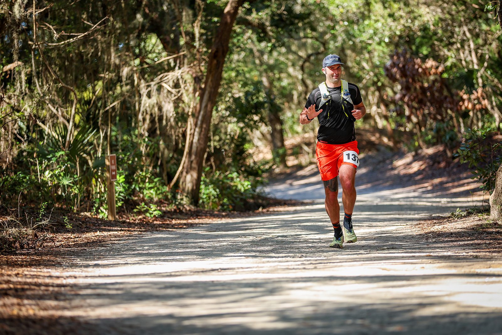 Runner on wide canopied trail through green maritime hammock