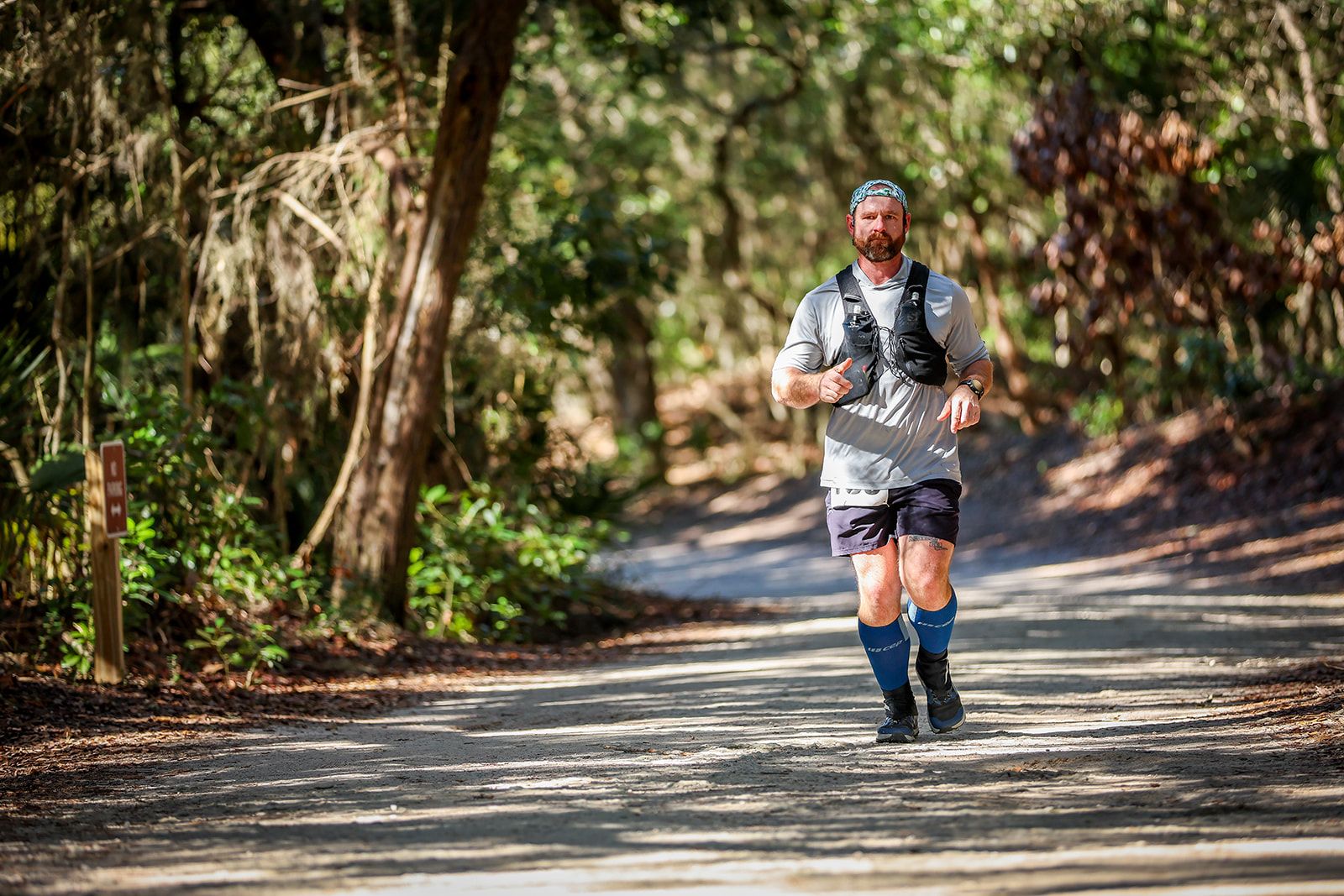 Runner with blue socks on lush green canopied trail