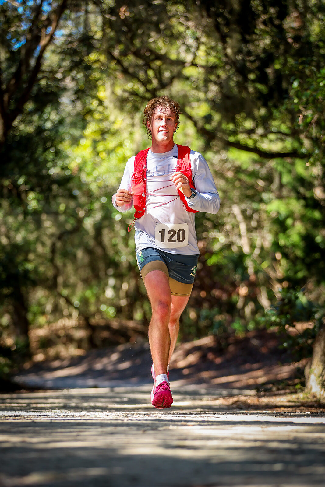 Runner under forest canopy with dappled light