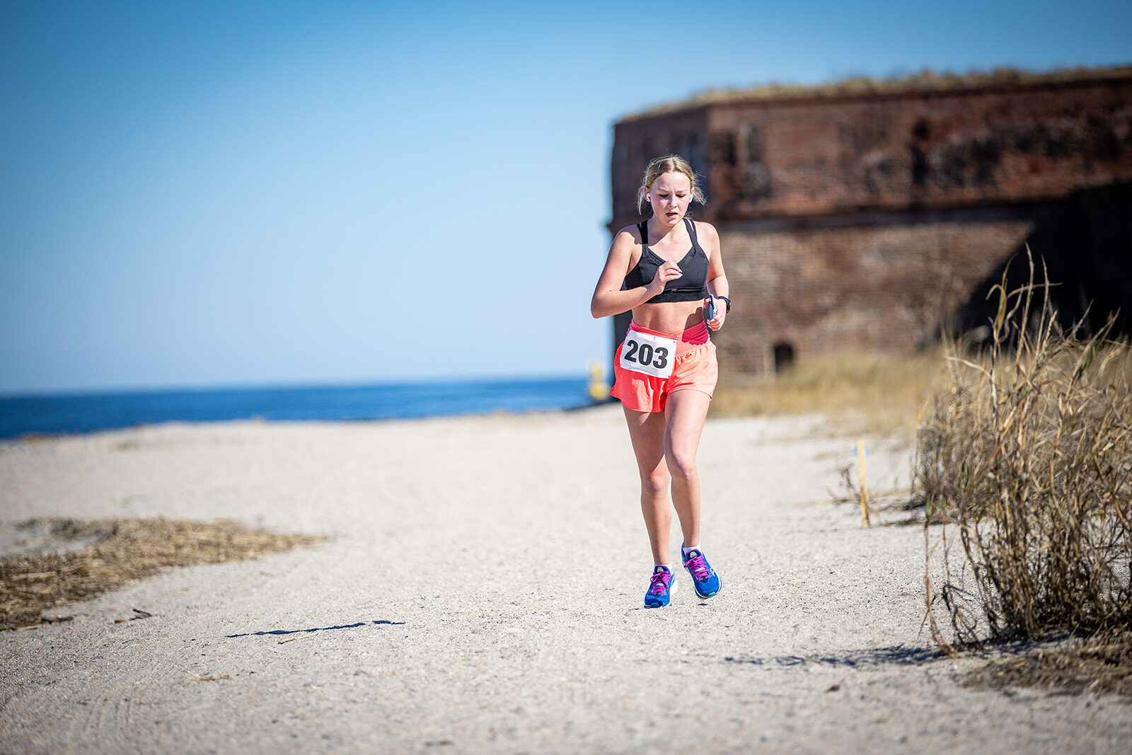 Runner on beach with historic fort wall and ocean