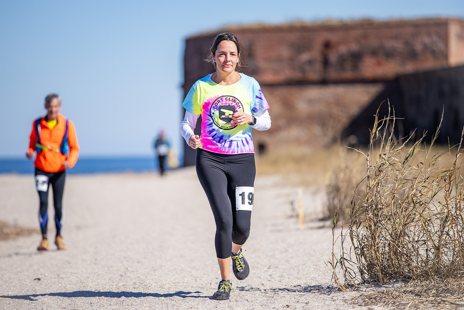 Woman in tie-dye Fort Clinch shirt near fort and ocean